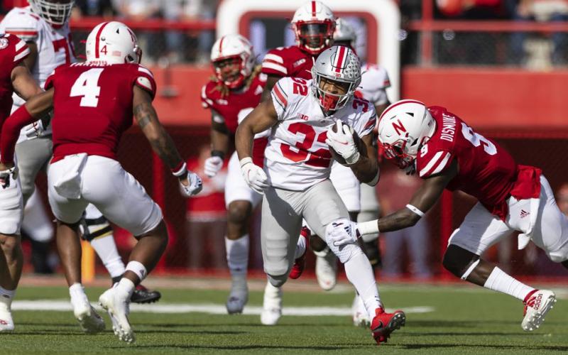Ohio State's TreVeyon Henderson (32) rushes against Nebraska's Myles Farmer (4) and Marquel Dismuke (9) during Saturday’s game at Memorial Stadium in Lincoln, Neb. Ohio State defeated Nebraska 26-17. (REBECCA S. GRAZT/Associated Press)