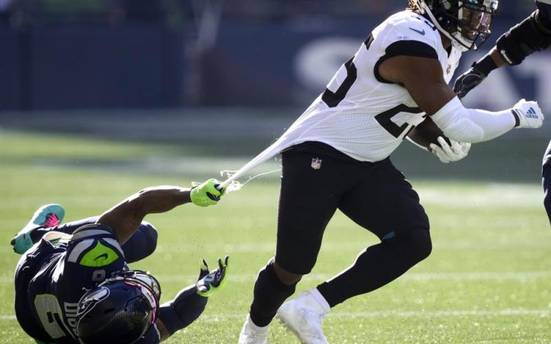 Jacksonville Jaguars running back James Robinson, right, is grabbed by his jersey by Seattle Seahawks free safety Quandre Diggs on Oct. 31 in Seattle. (STEPHEN BRASHEAR/Associated Press)
