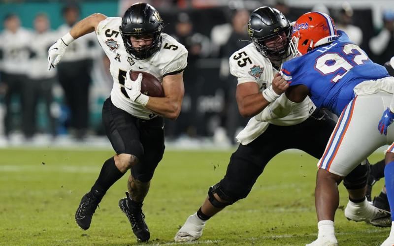 Central Florida running back Isaiah Bowser (5) follows a block by offensive lineman Matthew Lee (55) on Florida defensive lineman Jalen Lee during the Gasparilla Bowl on Thursday in Tampa. (CHRIS O’MEARA/Associated Press)