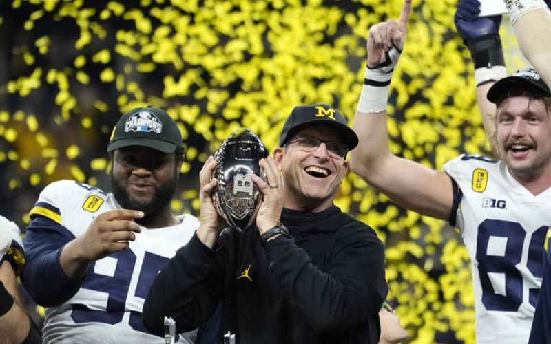 Michigan coach Jim Harbaugh celebrates with the team after winning the Big Ten championship against Iowa, 42-3, on Dec. 4 in Indianapolis. It was the Wolverines' first Big Ten title in 17 years, which clinched a berth in the College Football Playoff. (AP File)