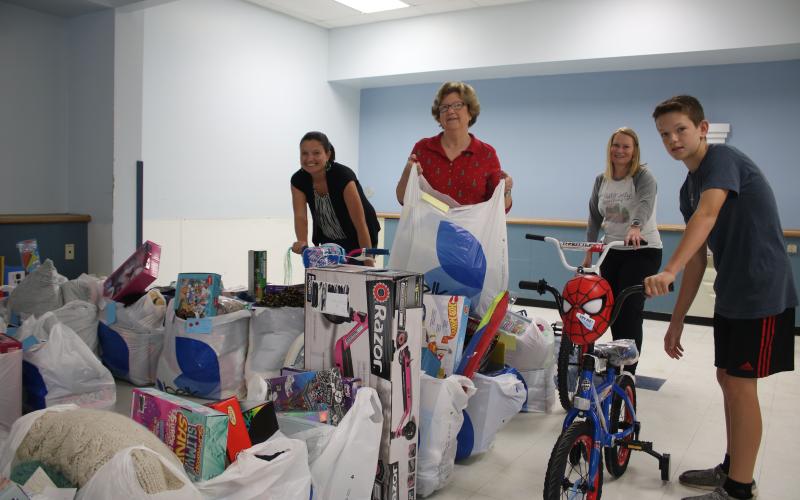 Christmas Dream Machine volunteers Jennifer Munroe (from left), Janet Stanford, Angela Towns and Walker Munroe, organize toys for the Christmas Dream Machine Toy Distribution which took place Sunday afternoon. (TONY BRITT/Lake City Reporter)