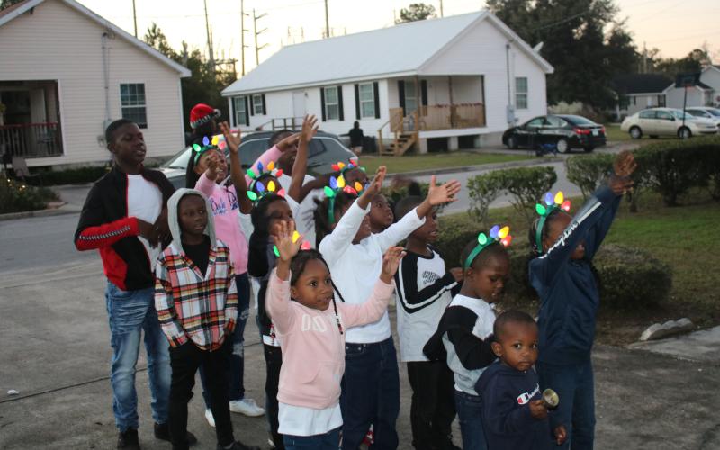 Children gather in the driveway of an Aberdeen home to sing Christmas carols on Wednesday afternoon. (TONY BRITT/Lake City Reporter)