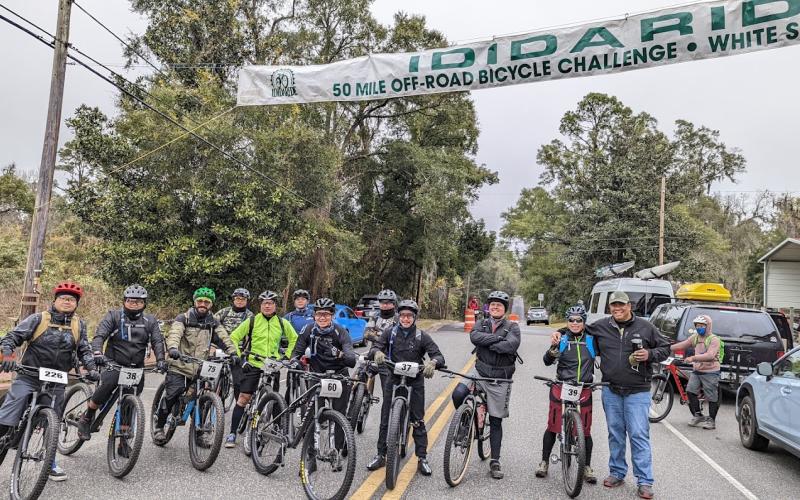 Bikers participating in the 2022 IDIDARIDE pose underneath a banner marking the event. More than 300 participants rode through the off-road courses set up for the 50-mile challenge. (COURTESY)