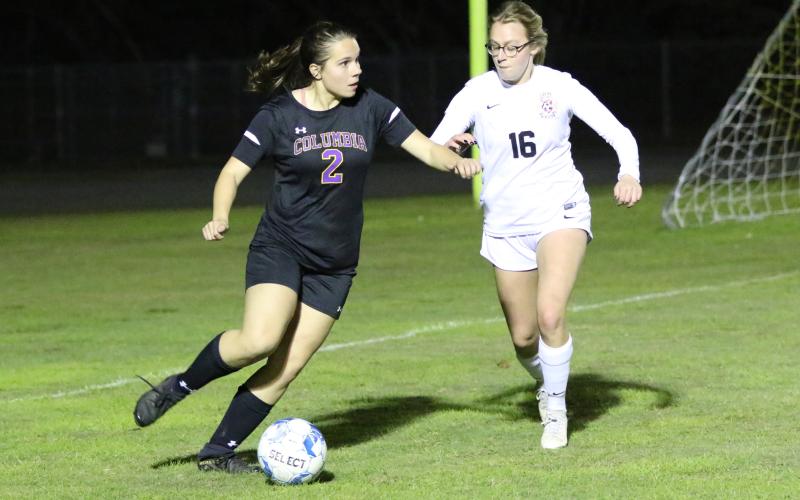 Columbia’s Hannah Dicks looks to pass to a teammate as Leon’s Emerson Jones rushes over to defend during Friday’s match. (MORGAN MCMULLEN/Lake City Reporter)