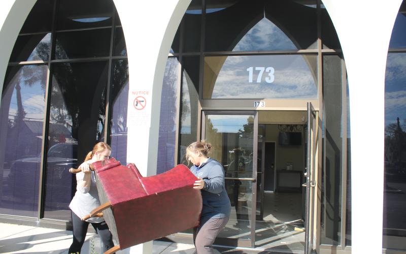 Lake City Customer Service Manager Katrina Medearis (left) and Brandy McGhin, city customer service coordinator, move furniture into the Millennium Bank building Thursday afternoon. (TONY BRITT/Lake City Reporter)