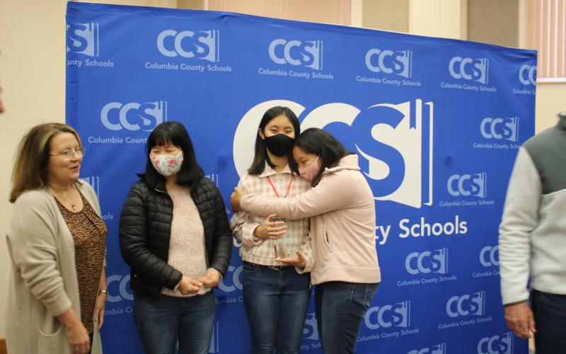 Cindy Kim (center) gets a hug from her sister, Arienna, alongside their mother, Ae-yun Shin. (TONY BRITT/Lake City Reporter)