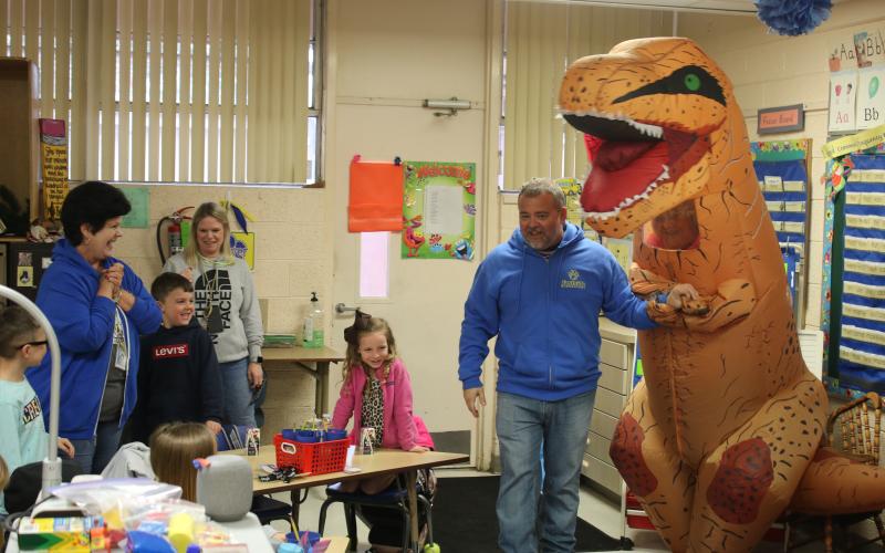 Roger Little (right), Eastside Elementary School principal, holds the hand of ‘Trixie The T-Rex’ as he introduces her to Terry Brewer’s kindergarten class. (TONY BRITT/Lake City Reporter)