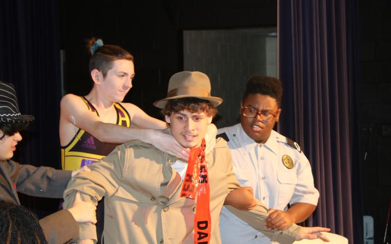 Columbia High School student Kaiden Hodson is grabbed by Colin Jolliffee and Schmari Lockley during Wednesday’s dress rehearsal for the ‘Murder at the Orient Express’ mystery dinner theater production scheduled for Friday night. (TONY BRITT/Lake City Reporter)