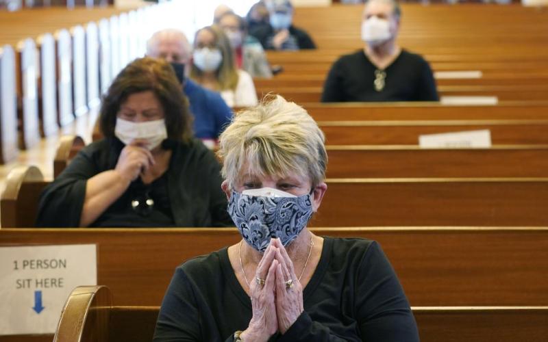 Diane Leahy prays with others before receiving the second dose of the Moderna covid-19 vaccine at St. Patrick Catholic Church on March 1, 2021, in Miami Beach. (MARTA LAVANDIER/Associated Press)