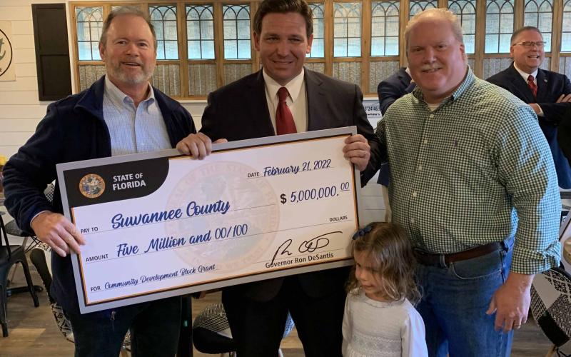 Gov. Ron DeSantis and his daughter Madison present a check to Suwannee County Administrator Randy Harris (left) and Shannon Roberts on Monday at an appearance in Madison. (COURTESY)