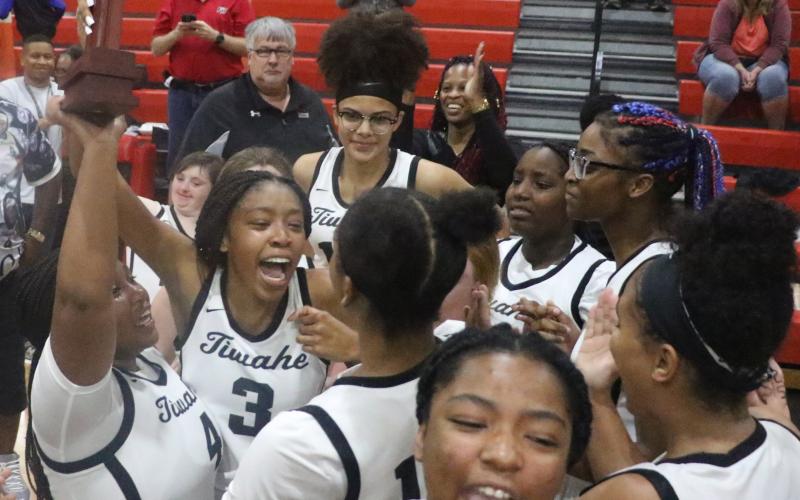 The Fort White girls basketball team hoists the District 6-1A Championship trophy in the air as it celebrates the program’s first district title Friday night. (MORGAN MCMULLEN/Lake City Reporter)