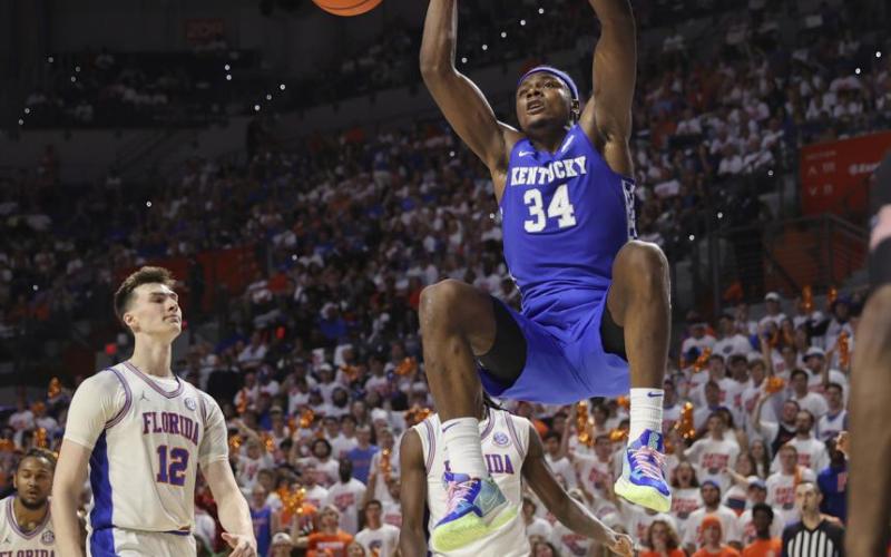 Kentucky forward Oscar Tshiebwe (34) dunks next to Florida forward Colin Castleton (12) during Saturday’s game in Gainesville. (MATT STAMEY/Associated Press)