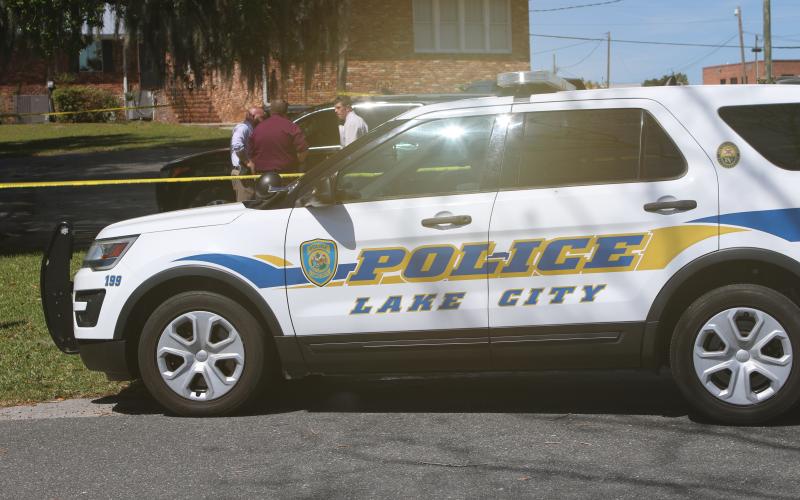 LCPD detectives huddle up in a parking lot near Lake DeSoto Monday morning following a report of two dead bodies in a vehicle. (JAMIE WACHTER/Lake City Reporter)