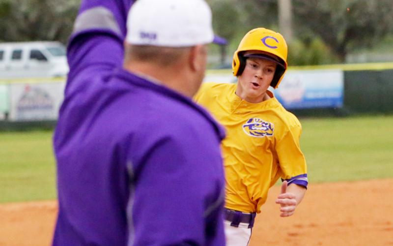 Columbia head coach Chris Howard (left) waves home Columbia outfielder Branson Mann as he rounds third base for a run against Gainesville on Friday night. (BRENT KUYKENDALL/Lake City Reporter)