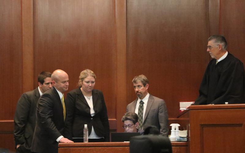 Representatives for both the prosecution and defense — including State Attorney John Durrett (second from left) and defense attorneys Allison Miller (third from left) and Nathan Marshburn (second from right) — and Judge Paul Bryan (right) gather around the court’s stenographer to review a piece of testimony Thursday afternoon at the Columbia County Courthouse. (MORGAN MCMULLEN/Lake City Reporter)