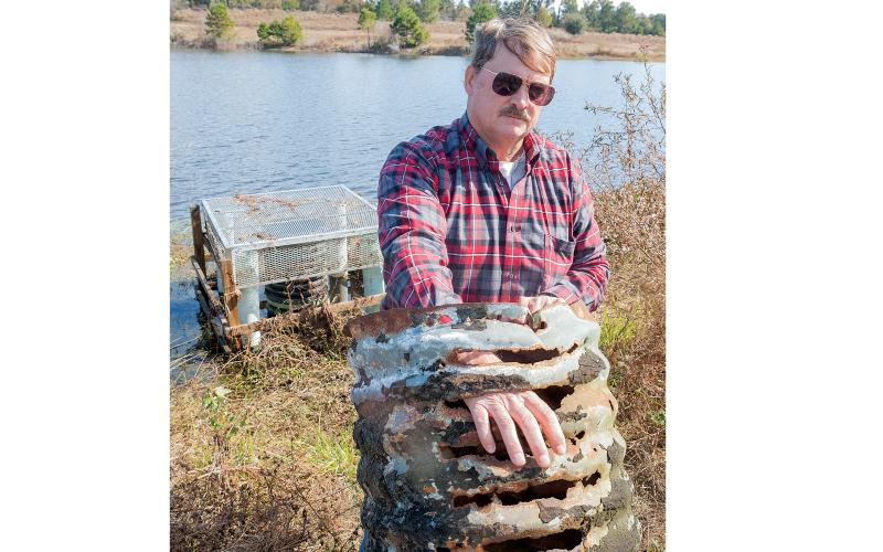 In this 2014 file photo, Jeffrey Hill poses with the rusty pipe at the heart of his dispute. (FILE)