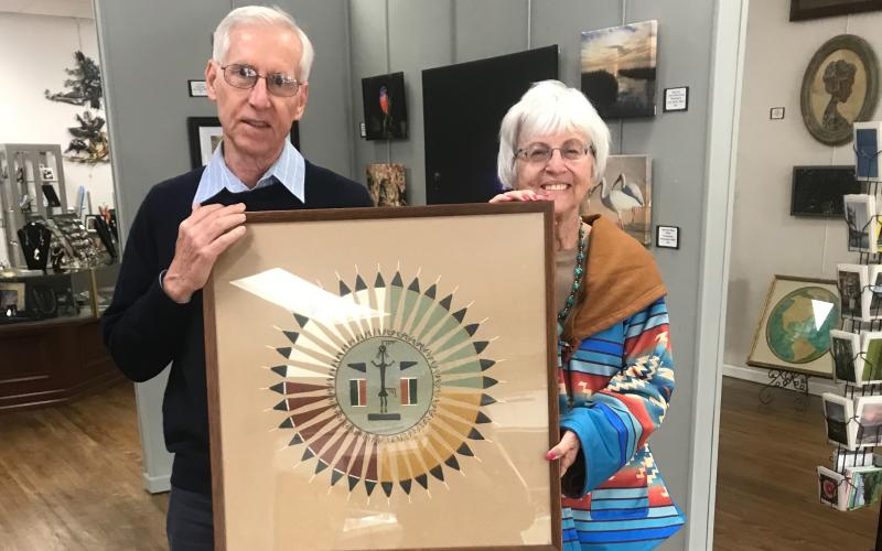 Jim Riley, past president of the Art League of North Florida/Gateway Art Gallery, receives one of the donations of the Harter Trust from Rose Pavey, Administrator. This piece is a Navajo sand painting and will be in the exhibit. (COURTESY)