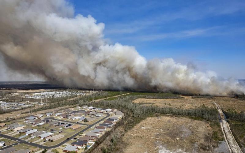 A fast-moving wildfire looms over homes outside of Panama City on Friday. More than 200 firefighters and emergency workers from throughout the Florida Panhandle worked overnight into Saturday, to strengthen containment lines and protect homes. (MIKE FENDER/News Herald/AP)