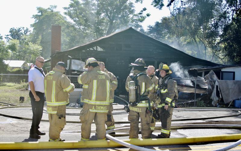 Columbia County Assistant Fire Chief Lance Hill (left) talks with firefighters after they extinguished the flames in a house fire Tuesday morning on SE Montrose Avenue. (TODD WILSON)