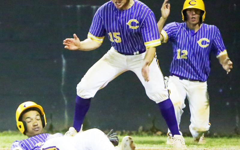 Columbia’s Brayden Thomas slides safely into home plate behind Truitt Todd (15) and Ty Jackson (12), who all scored on Kade Jackson’s bases-clearing double, in the sixth inning of Thursday’s game against Middleburg. (BRENT KUYKENDALL/Lake City Reporter)