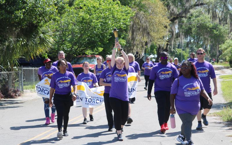 A participant in Tuesday’s Law Enforcement Torch Run for Special Olympics hoists the torch up above her head. (TONY BRITT/Lake City Reporter)