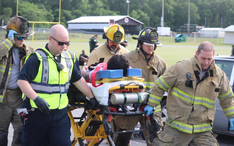 First responders aid a Fort White High School student who was portraying an injured person during a mock crash demonstration Thursday at the school. (TONY BRITT/Lake City Reporter)