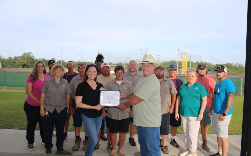 Columbia County Tourist Development Council Executive Director Paula Vann presents Clint Pittman, the county’s Landscapes and Parks director, a certificate Tuesday morning at Southside Sports Complex for helping advance tourism in the county as they are joined by TDC and park staff. (TONY BRITT/Lake City Reporter)