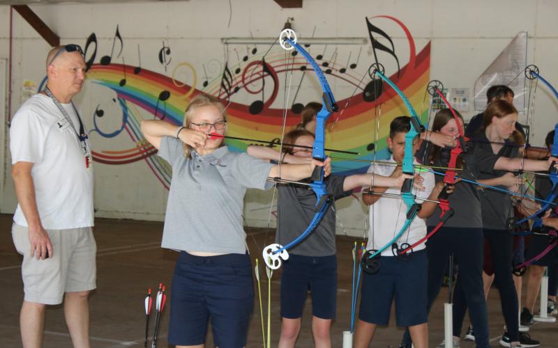 Marta Priller, 11, a member of the Belmont Academy Elementary archery team prepares to fire an arrow while assistant coach Keith Williams looks on. (TONY BRITT/Lake City Reporter)
