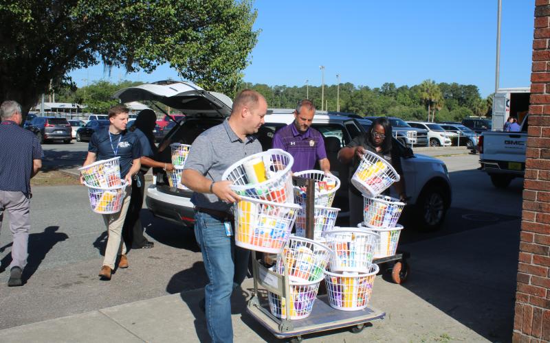 Trent Linn (from left), Lake City Correctional Facility Core Civic business manager, Daniel Taylor, Columbia High School principal Trey Hosford and Sonical Mitchell, local “baskets of love” onto trailers Thursday morning at Columbia High School. (TONY BRITT/Lake City Reporter)