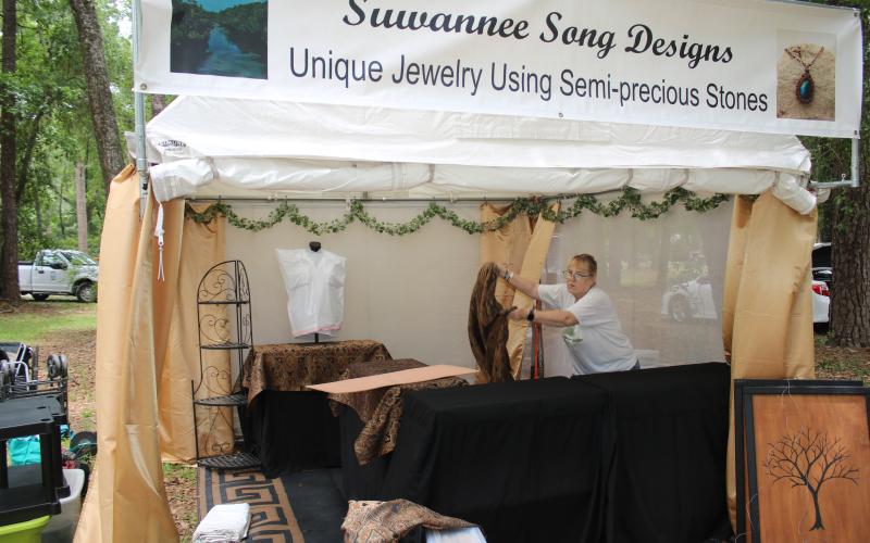 Lynne Hutchins, of Live Oak, sets up her Suwannee Song Designs booth at Stephen Foster Park for this weekend’s 70th annual Florida Folk Festival. (TONY BRITT/Lake City Reporter)