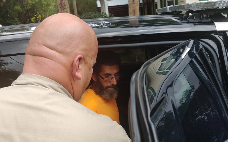 Thomas Walker (right) is placed in the back of a Live Oak Police Department vehicle after he was arrested Friday. (COURTESY)