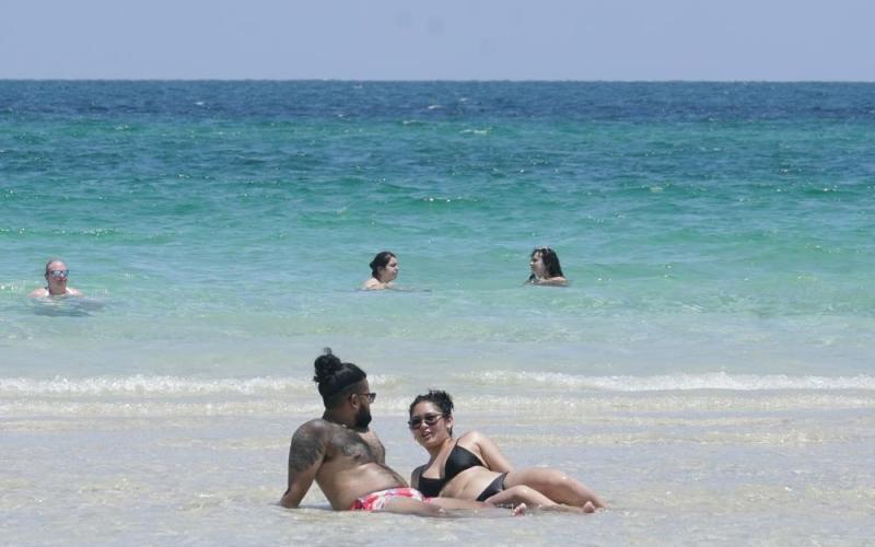 A couple sun bathes on a sand bar July 13 in Miami Beach. (MARTA LAVANDIER/Associated Press)