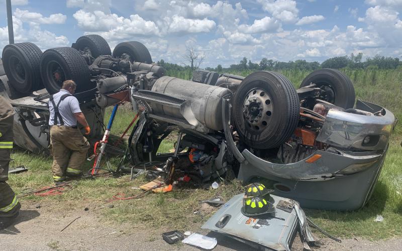 A member of Columbia County Fire Rescue looks at an overturned semi along U.S. Highway 27 in Suwannee County on Wednesday afternoon in which the driver was trapped and suffered serious injuries. (COURTESY SUWANNEE COUNTY FIRE RESCUE)