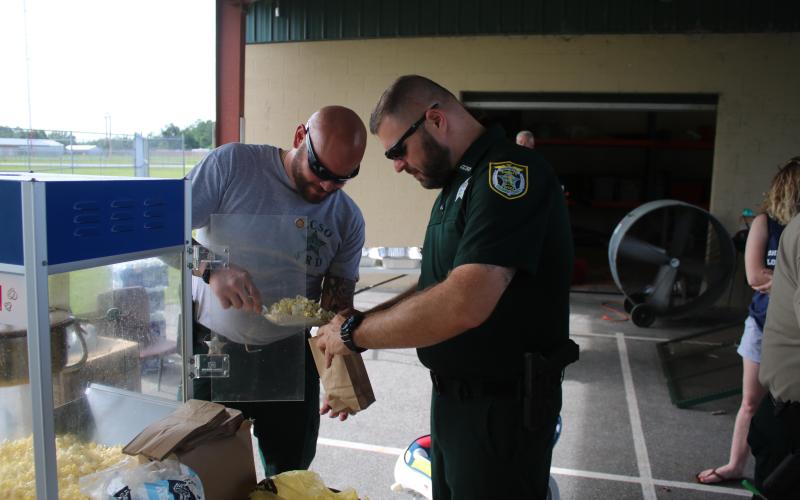 Columbia County Sheriff’s Office deputies Anthony Cortese and Mike Rodriguez bag up some popcorn at a ‘Summer Nights’ program last summer. (FILE)