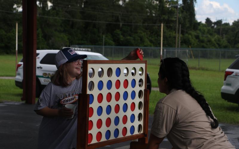 Keith Spence, 10, plays Connect Four with a Columbia County Sheriff’s Office school resource officer Friday during Summer Nights. (MORGAN MCMULLEN/Lake City Reporter)