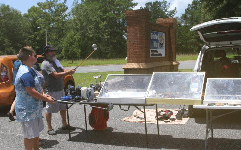 Prospective buyers take a closer look at a pair of golf clubs at Friday’s United Way of Suwannee Valley community yard sale. (TONY BRITT/Lake City Reporter)