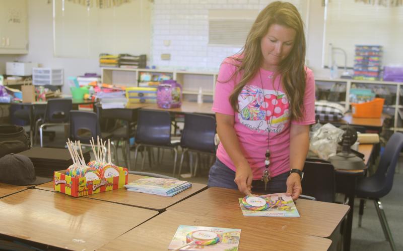 Amber Thomas, an Eastside Elementary School second grade teacher, sets a lollipop and book on desks Wednesday. (TONY BRITT/Lake City Reporter)