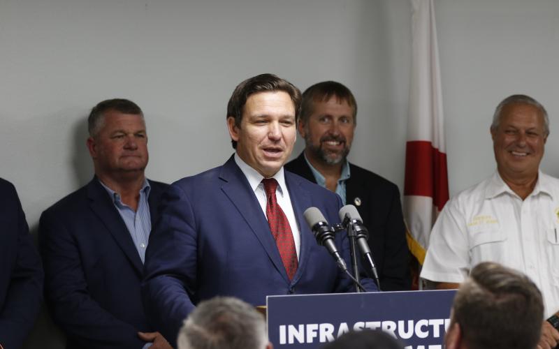 Florida Gov. Ron DeSantis awarded Suwannee County $1.9 million for water and wastewater improvements at its catalyst site during a press conference Tuesday. County Commissioners Franklin White (left) and Travis Land look on during the announcement. (JAMIE WACHTER/Lake City Reporter)