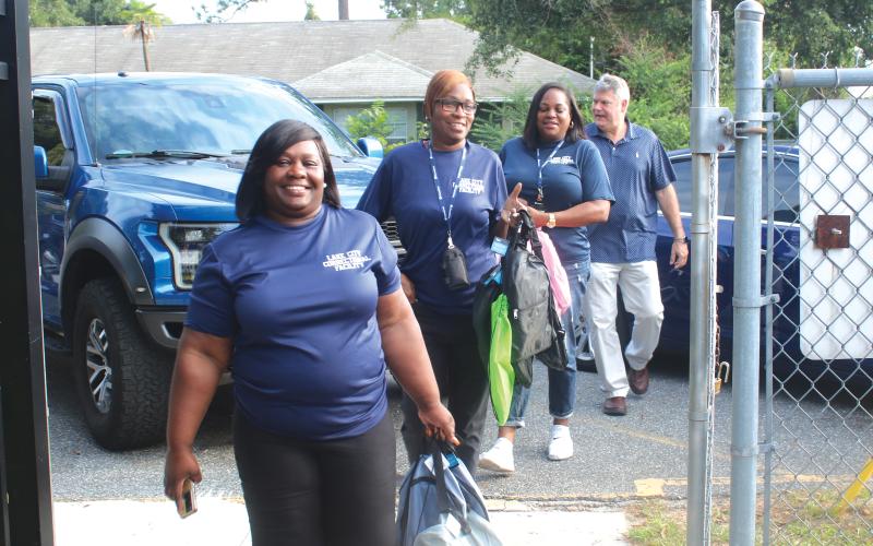 Lake City Correctional Facility employees Sonical Mitchell (from left), Twylah Queen, Deanna Lumpkin and James Deal, walk through the Eastside Elementary School gates Thursday morning while carry book bags for area students. The foursome donated book bags to several local elementary schools Thursday. (TONY BRITT/Lake City Reporter)