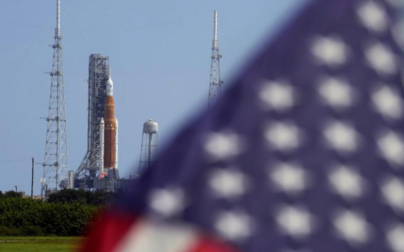 An American flag flies in the breeze as NASA's new moon rocket sits on Launch Pad 39-B after being scrubbed at the Kennedy Space Center on Saturday in Cape Canaveral. (CHRIS O’MEARA/Associated Press)