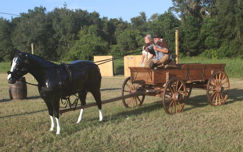 Todd and Tammy Denmark ride an antique wagon into Raven’s Hollow, the old west town depicted in their Denmark Acres site that will open Friday. (JAMIE WACHTER/Lake City Reporter)