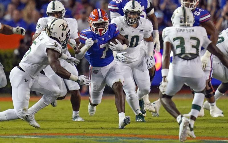 Florida running back Trevor Etienne finds an opening for yardage against the South Florida defense, including linebacker Antonio Grier (left), defensive lineman Nick Bags (second from right) and cornerback T-Mac Simpson (33), during Saturday's game in Gainesville. (JOHN RAOUX/Associated Press)