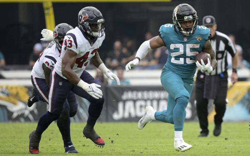Jacksonville Jaguars running back James Robinson (25) runs past Houston Texans defensive tackle Jaleel Johnson (93) and middle linebacker Neville Hewitt (43) on Dec. 19, 2021, in Jacksonville. (AP FILE)