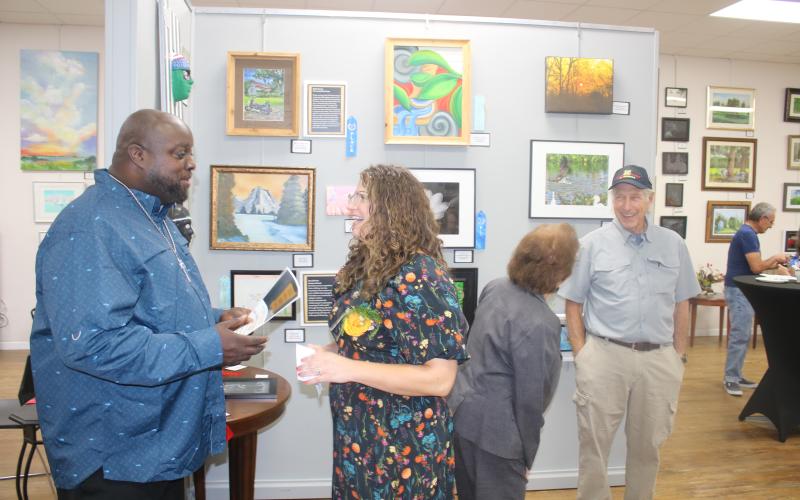 Osmund Johnson (left) shares a laugh with Sarah Stephens, the VA’s creative arts therapist, during Monday night’s veterans art exhibit award ceremony at the Gateway Art Gallery. (TONY BRITT/Lake City Reporter)