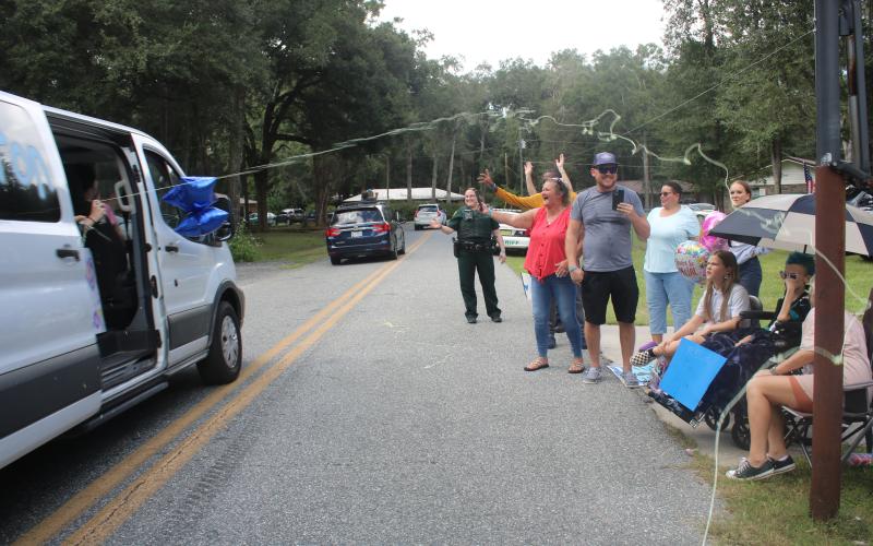 Belmont Academy students shoot silly string out of a van at Peyton Hamilton (under umbrella) and her family members during Monday’s parade. (TONY BRITT/Lake City Reporter)