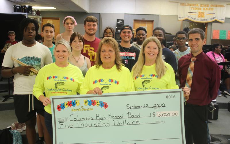 Puzzle Pieces of North Florida representatives Tabatha Feagle (from left), Kathryn Harper and Terri Prescott stand with Jay Miller, Columbia High School band director, after presenting the band with a $5,000 check on Thursday afternoon. (TONY BRITT/Lake City Reporter)