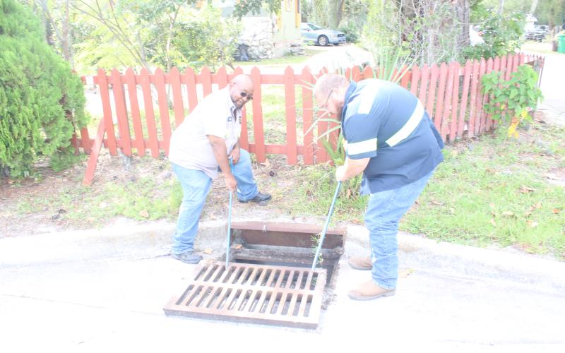 Pic Redmond (left) and Josh Green, employees with the City of Lake City Public Works Department, close a storm drain on Northwest Texas Avenue after inspecting it for blockages before inclement weather from Hurricane Ian arrives. (TONY BRITT/Lake City Reporter)