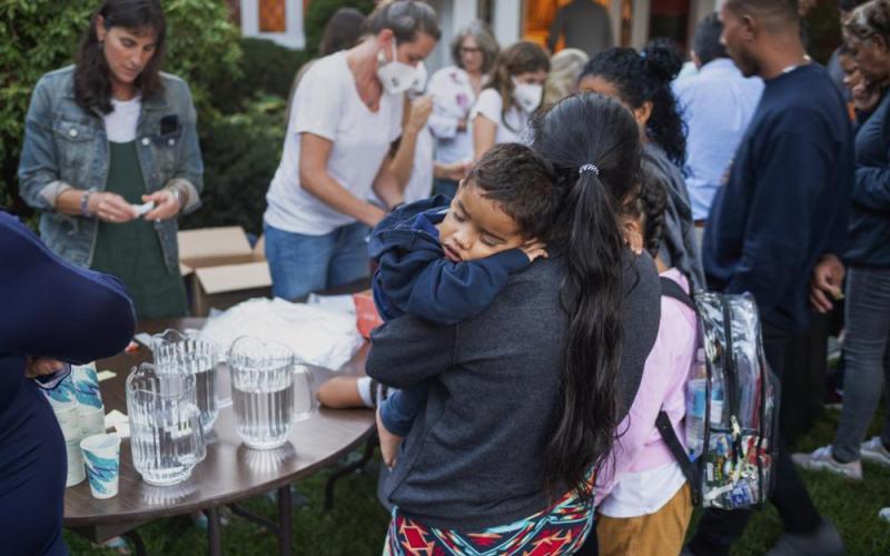 A woman, who is part of a group of immigrants that had just arrived, holds a child as they are fed outside St. Andrews Episcopal Church, Wednesday Sept. 14, in Edgartown, Mass., on Martha’s Vineyard. Florida Gov. Ron DeSantis on Wednesday flew two planes of immigrants to Martha’s Vineyard, escalating a tactic by Republican governors to draw attention to what they consider to be the Biden administration’s failed border policies. (RAY EWING/Vineyard Gazette via AP)