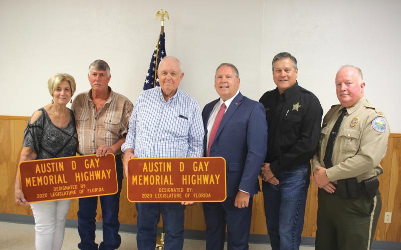Teresa Register (from left) stands with her brothers Tevis Gay, Dewy Gay, State Rep. Chuck Brannan, Columbia County Sheriff Mark Hunter and Col. James Wiggins, Florida Director of the Office of Agricultural Law Enforcement, following a ceremony where a portion of U.S. Highway 441 was dedicated in honor of slain agricultural officer Austin D. Gay.  The ceremony took place Friday morning at the Deep Creek Community Center. (TONY BRITT/Lake City Reporter)