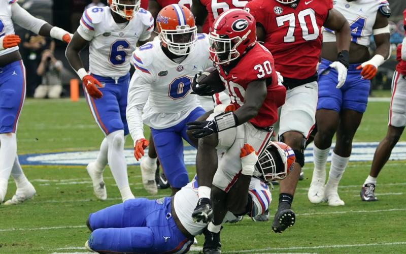 Georgia running back Daijun Edwards is stopped by Florida linebacker Antwaun Powell-Ryland Jr., bottom and safety Trey Dean III (0) during Saturday’s game in Jacksonville. (JOHN RAOUX/Associated Press)